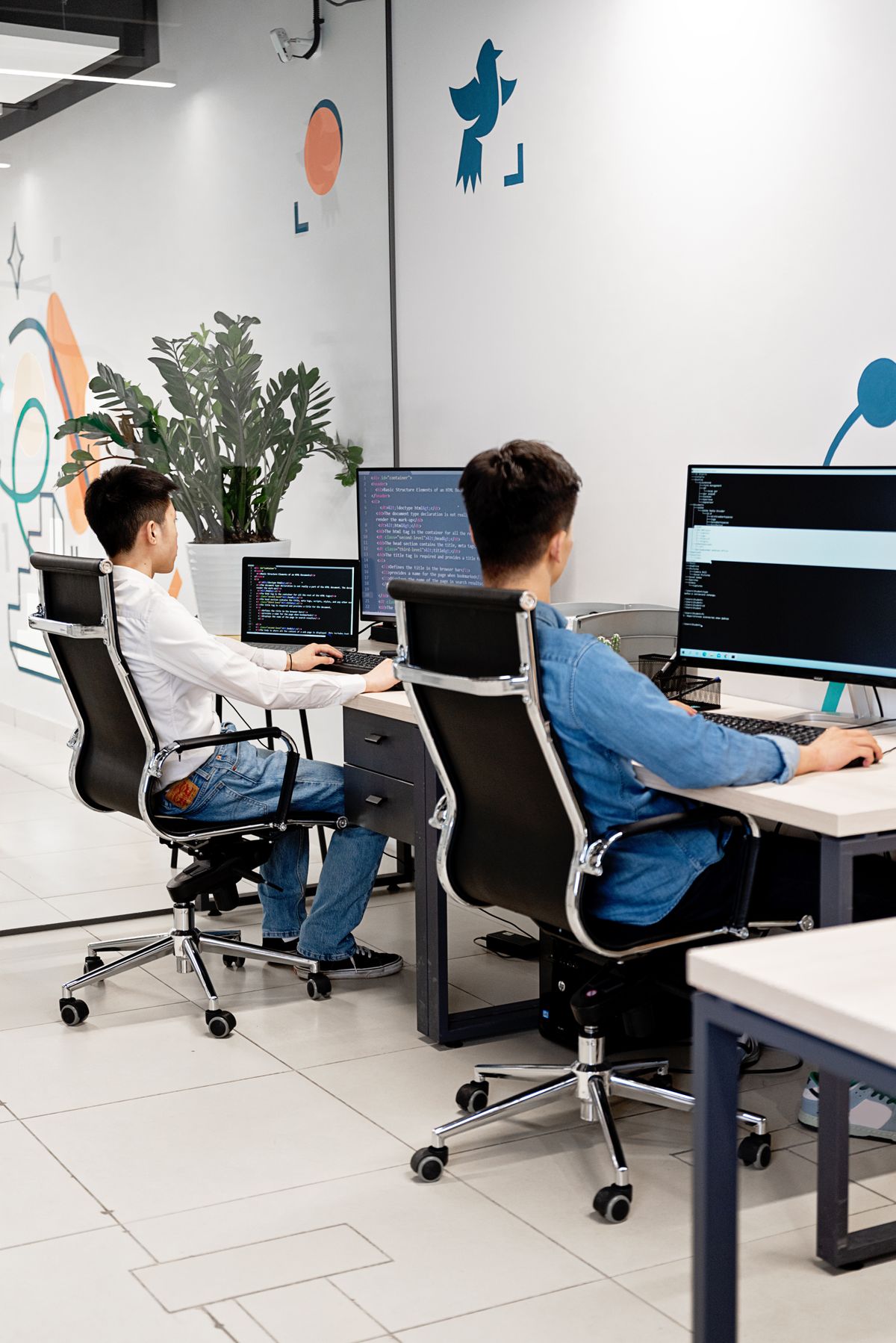 Duas pessoas trabalhando em computadores num escritório de tecnologia